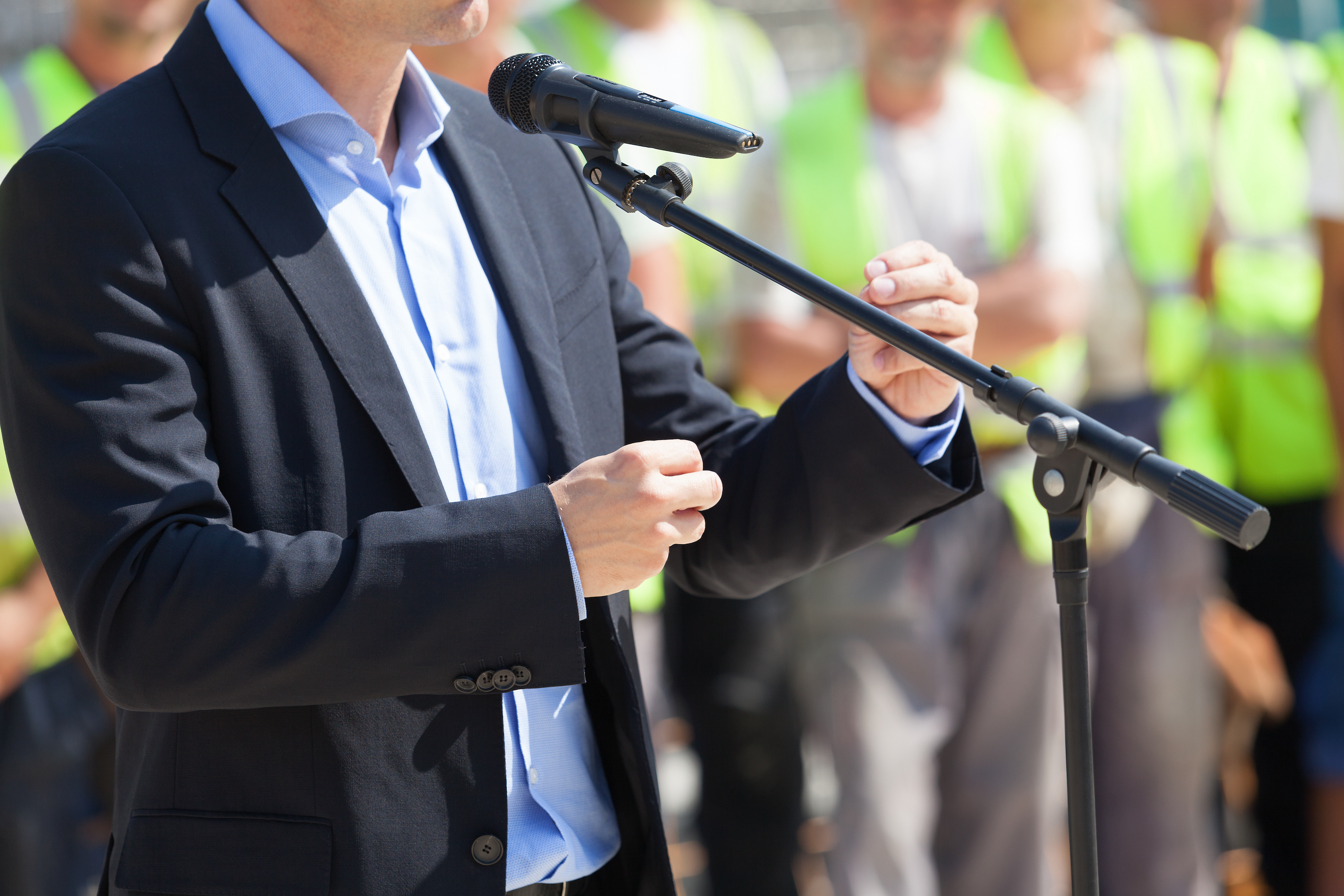 Imagen de político hablando por micrófono al público.